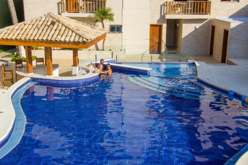瓜鲁雅Strand Hotel Guarujá Frente Mar的两人坐在大型蓝色游泳池