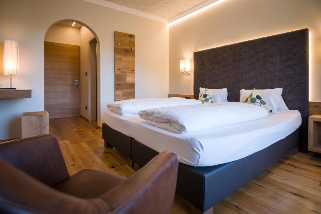拉纳Hotel Garni Vigilhof的一间卧室配有一张大床和一把椅子