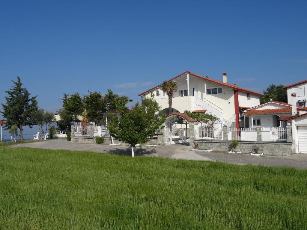 尼亚伊拉克利亚Villa Tikozidis的白色的房子,有栅栏和绿色庭院