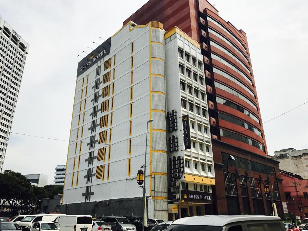 吉隆坡Swiss Hotel Kuala Lumpur的停车场内有车辆停放的高楼