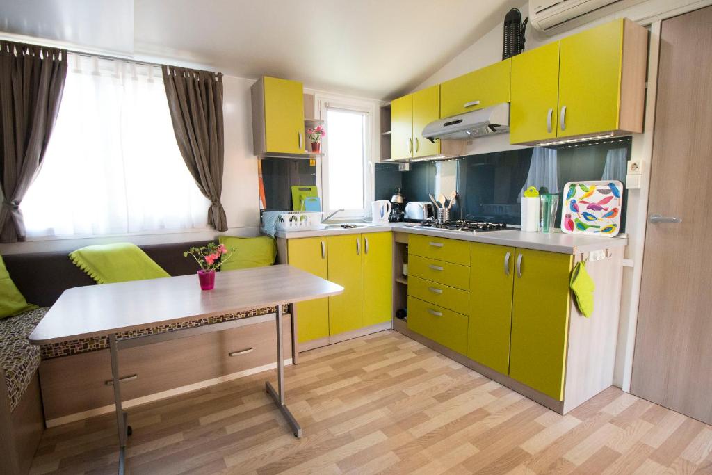 杜纳维德Mobile Home的厨房配有黄色橱柜和桌子