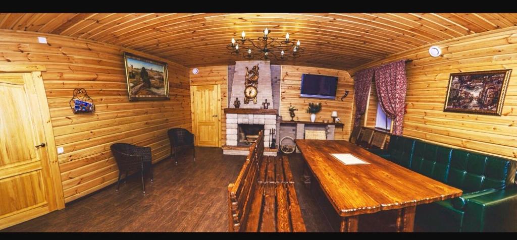 UzynHotel Bannyi Dvor的木房设有木桌和壁炉
