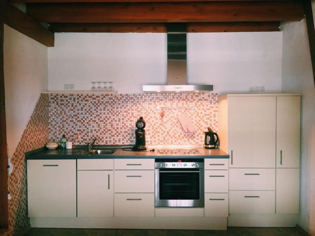 霍根海姆Biohof Zahn的厨房配有白色橱柜和炉灶烤箱。