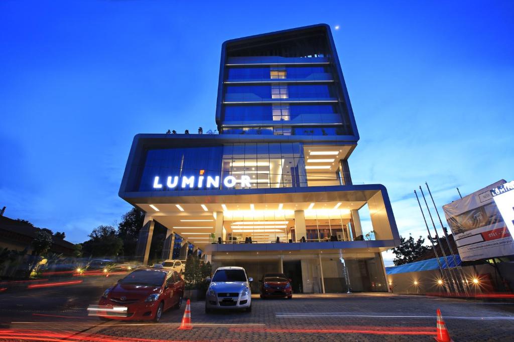 占碑市Luminor Hotel Jambi Kebun Jeruk By WH的停车场内有车辆的建筑物
