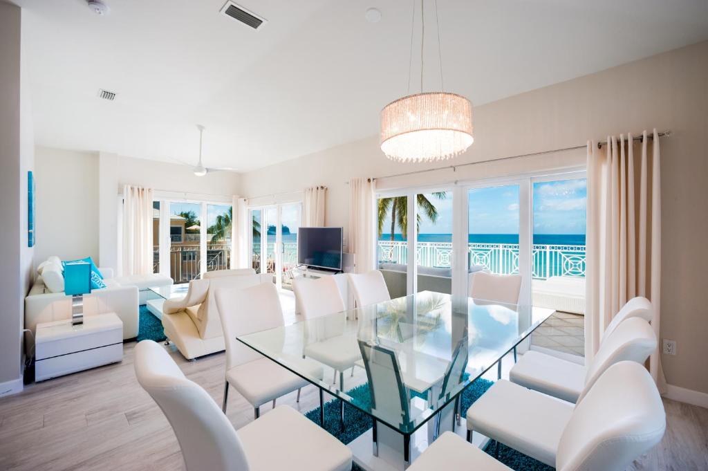 乔治敦Regal Beach Club的客厅配有玻璃桌和白色椅子