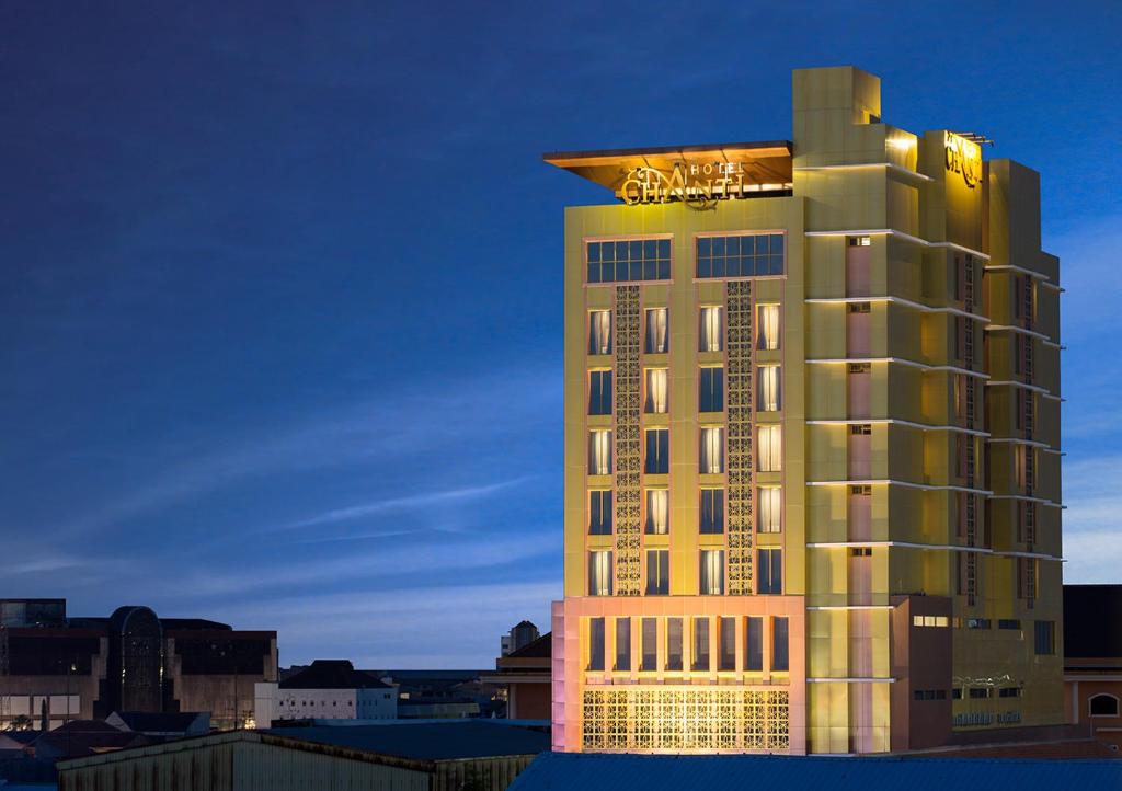 三宝垄印度尼西亚滕特雷姆酒店管理经营香蒂酒店的一座高大的旅馆建筑,上面有灯光标志
