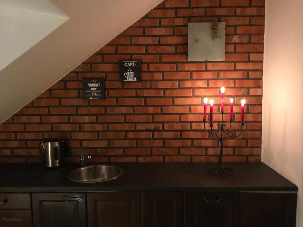 卡托维兹Apartamenty Madera的厨房配有水槽和带蜡烛的砖墙