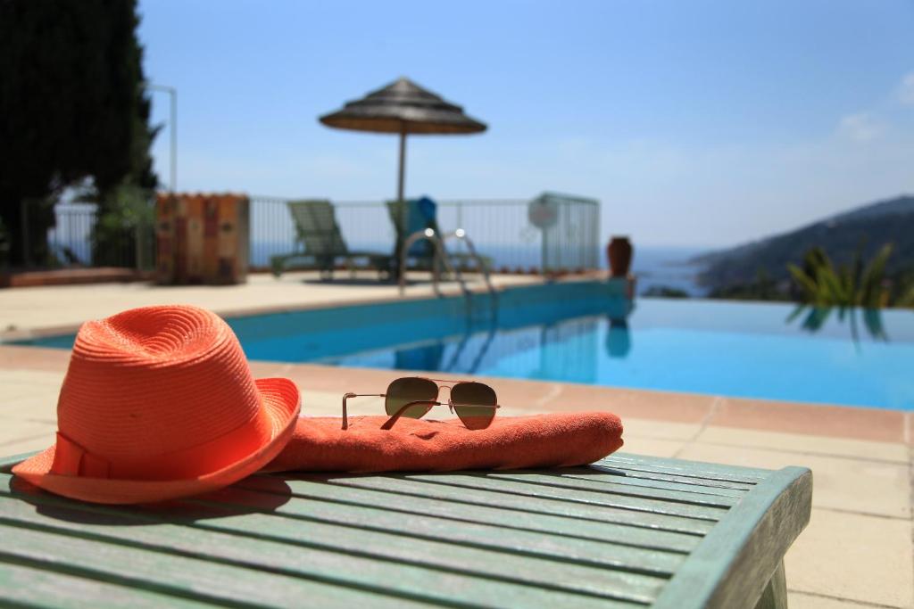 卡尔热斯艾阿丽威图公寓酒店的坐在游泳池旁长凳上的帽子和太阳镜
