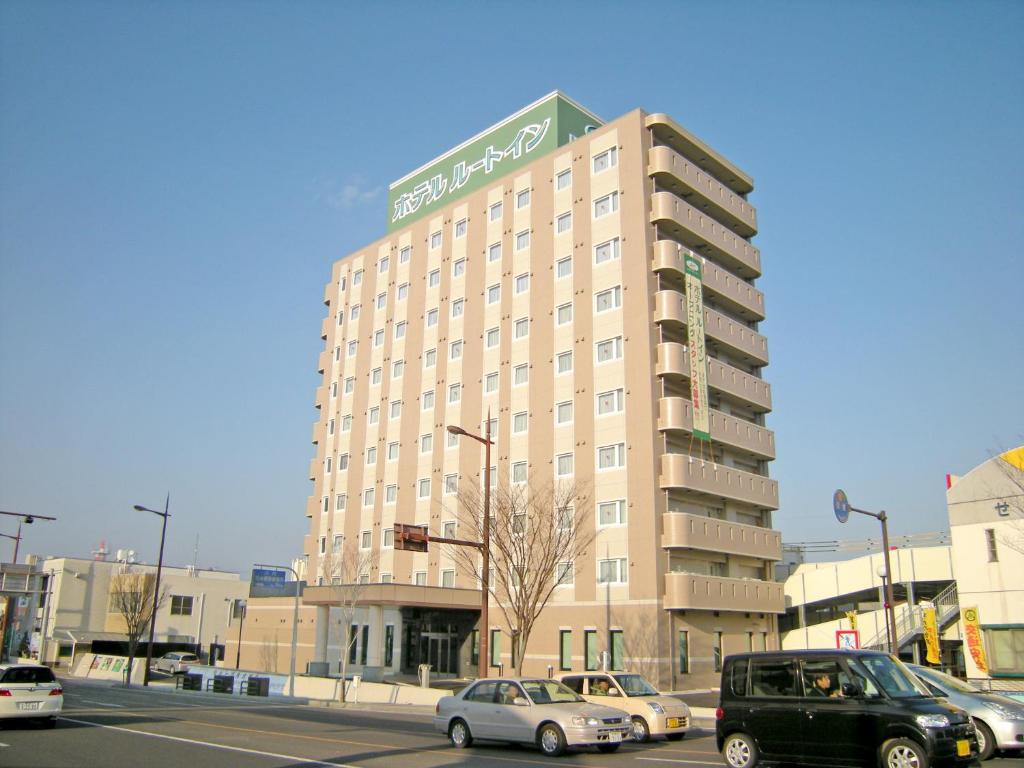 萨摩川内市萨摩川内茹特酒店的一座大型建筑,前面有汽车停放