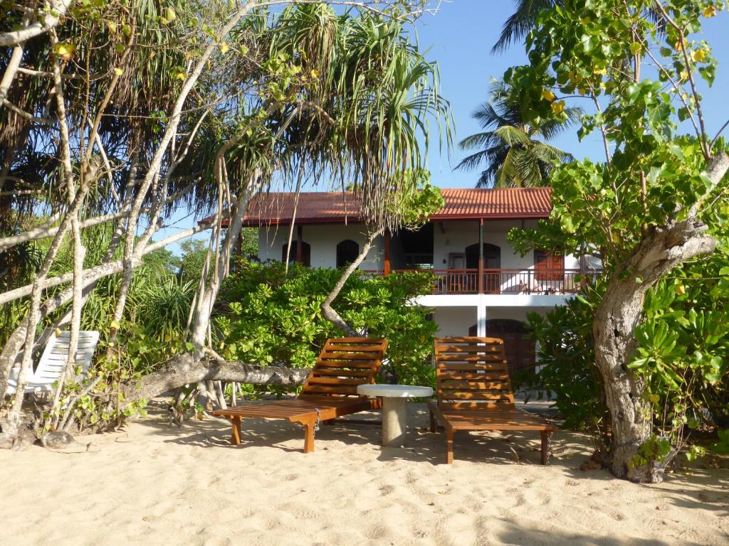 坦加拉Villa Sunrise的房屋前的海滩上摆放着两把椅子和一张桌子