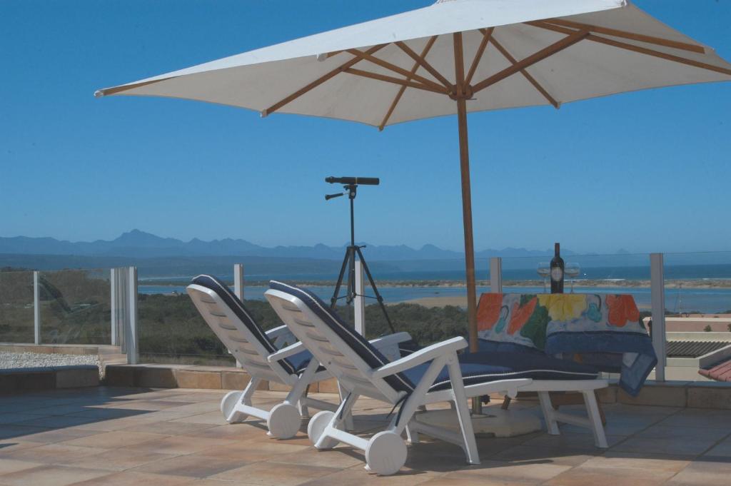 普利登堡湾Thanda Vista的两张椅子和一张带雨伞的桌子