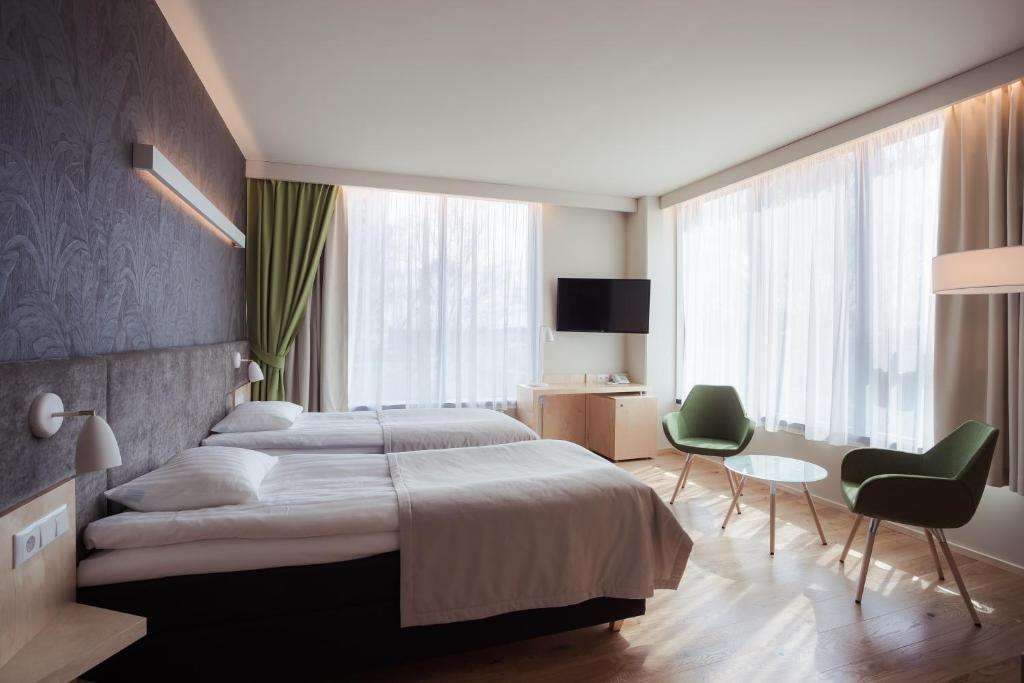 塔尔图塔尔图酒店的一间卧室配有一张大床和两张绿色椅子