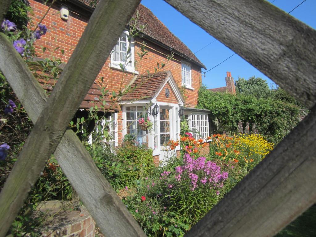 法纳姆Vine Cottage的一座房子,前面有一个种着鲜花的花园