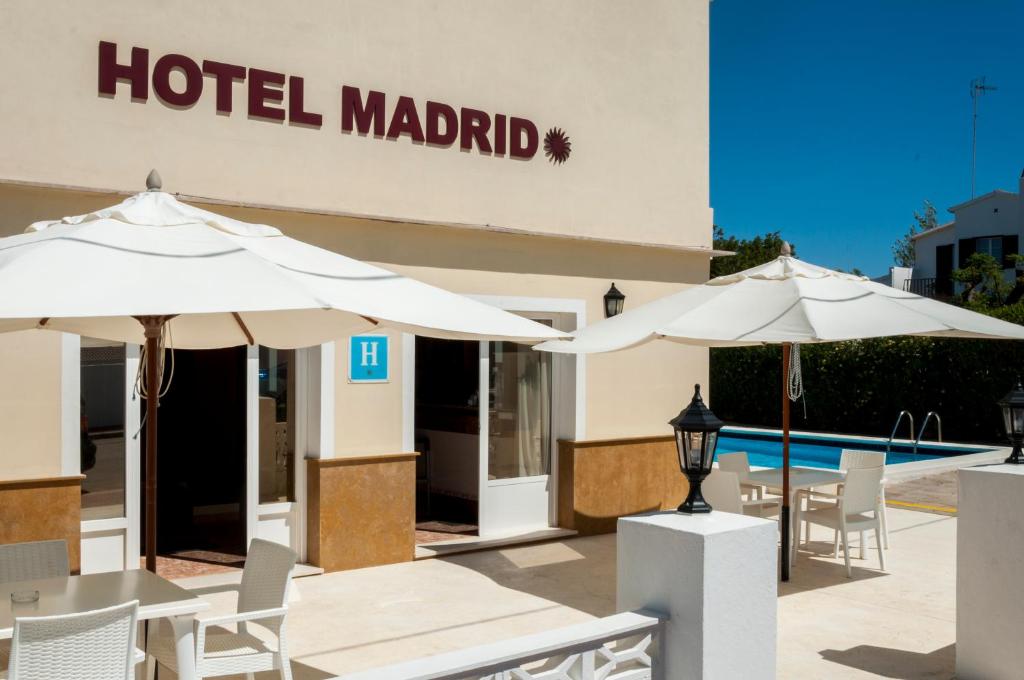 休达德亚马德里酒店的游泳池旁的一间酒店,配有桌子和遮阳伞