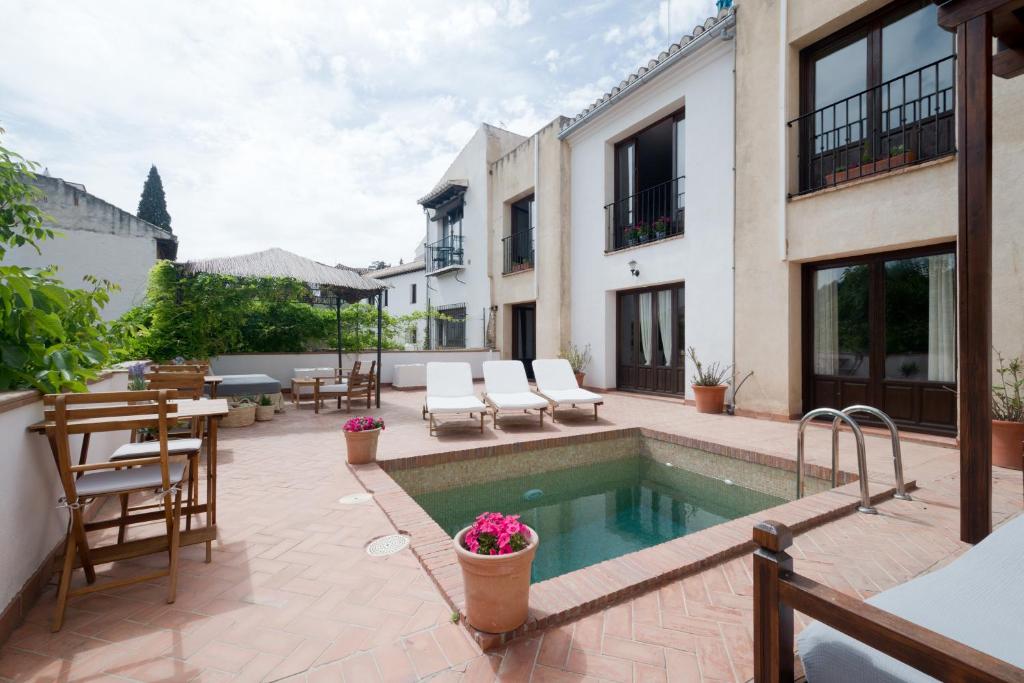 格拉纳达卡萨邦博酒店的户外庭院设有游泳池和桌椅。
