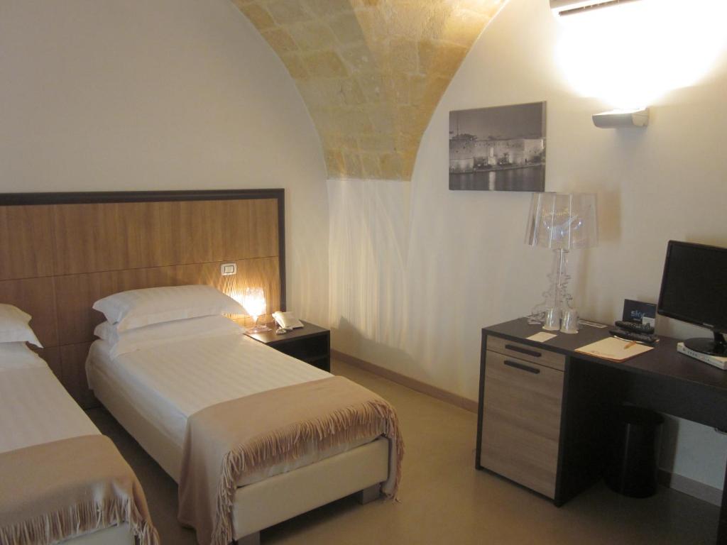 塔兰托阿尔贝尔格德索乐酒店的一间卧室配有两张床和一张带电脑的书桌
