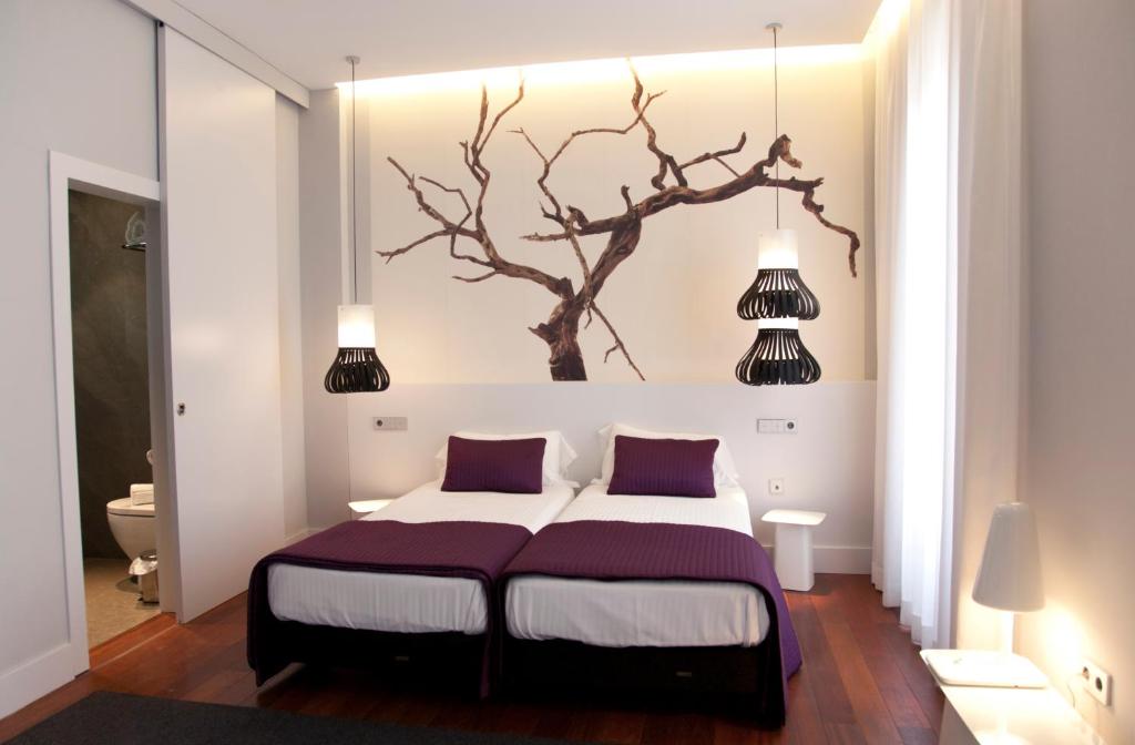格拉纳达孔湖酒店的卧室配有一张床铺,墙上挂着一棵树