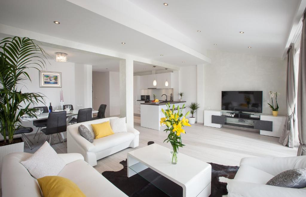 马卡尔斯卡Modern Apartman Pjero的一间客厅,配有白色家具,客厅拥有黄色的鲜花