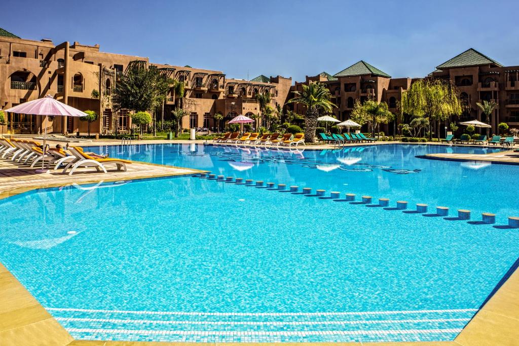 马拉喀什棕榈广场温泉酒店的度假村内带椅子和遮阳伞的大型游泳池