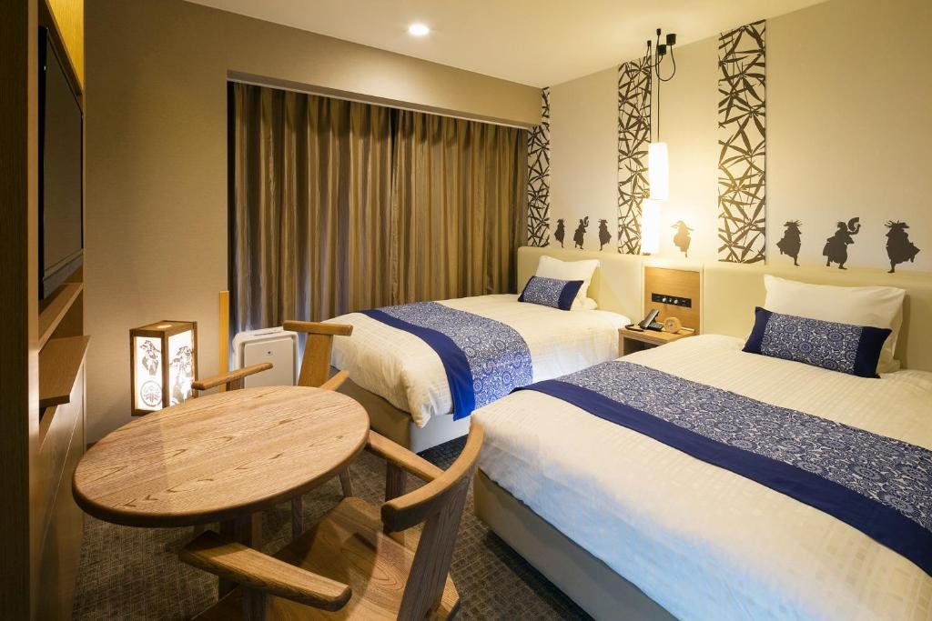 北上市JR-East Hotel Mets Kitakami的酒店客房设有两张床和一张桌子。