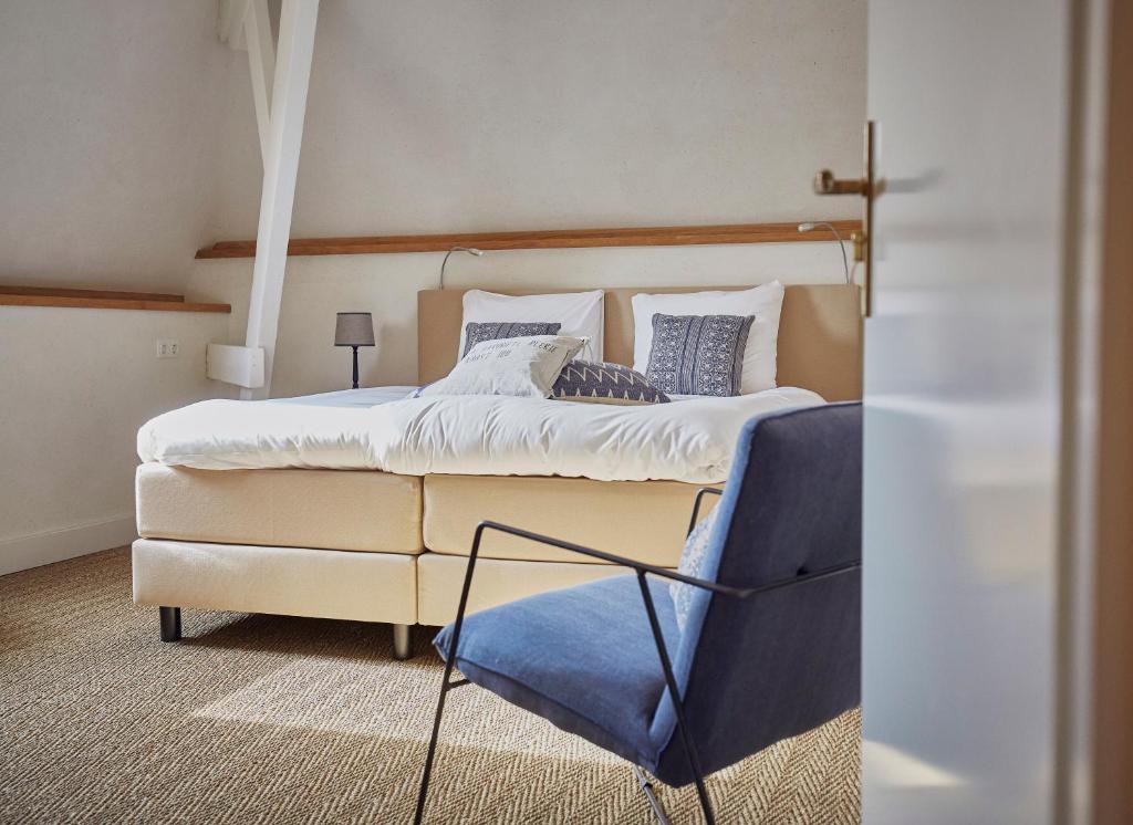 古尔彭Herberg de Zwarte Ruiter的一间卧室配有一张大床和一张蓝色椅子