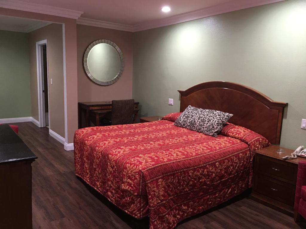 英格尔伍德美国LAX机场套房酒店的一间卧室配有一张带红色被子和镜子的床