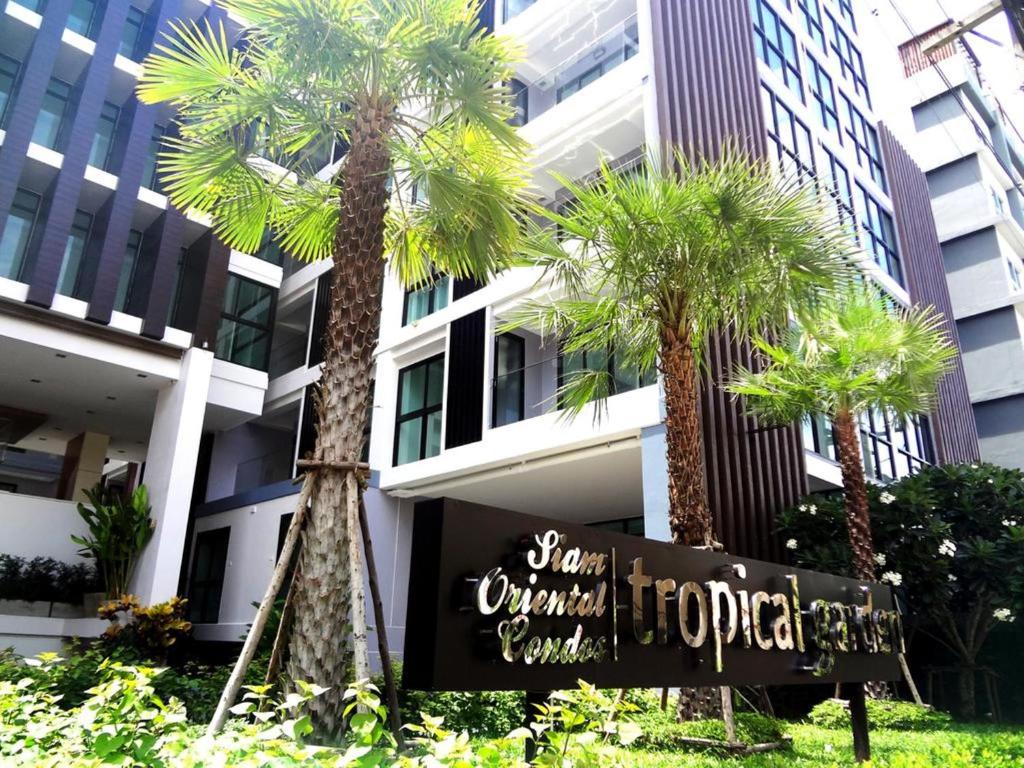 南芭堤雅热带花园一室公寓的棕榈树建筑前的酒店标志