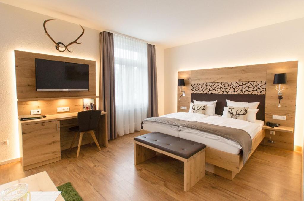 托特瑙Das Waldhotel - Genuss & Wellness am Notschreipass的一间卧室配有一张床、一张书桌和一台电视