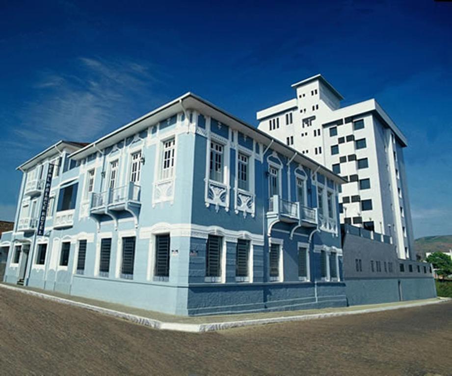 圣丽塔-杜萨普卡伊Real Palace Hotel的一座蓝色和白色的建筑,毗邻一座高大的建筑