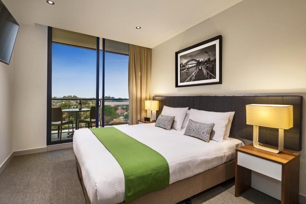 悉尼查茨伍德探索服务酒店的一间卧室设有一张大床和一个大窗户