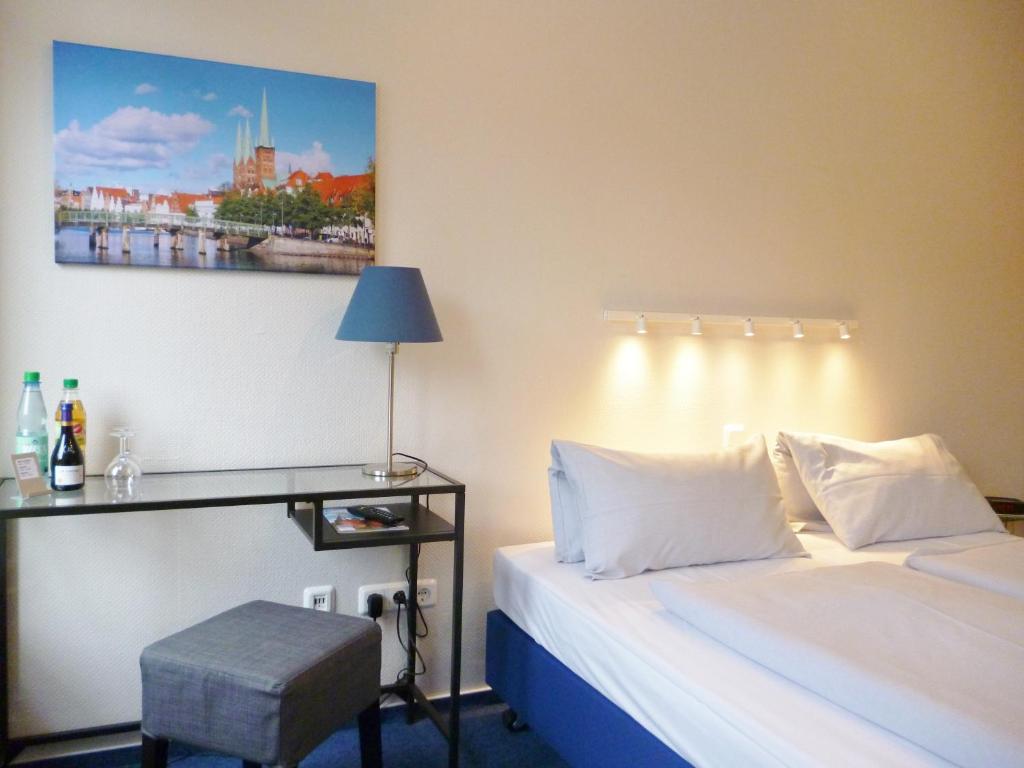 吕贝克姆勒特赫酒店的一间卧室配有一张床和一张桌子,墙上挂着一张照片