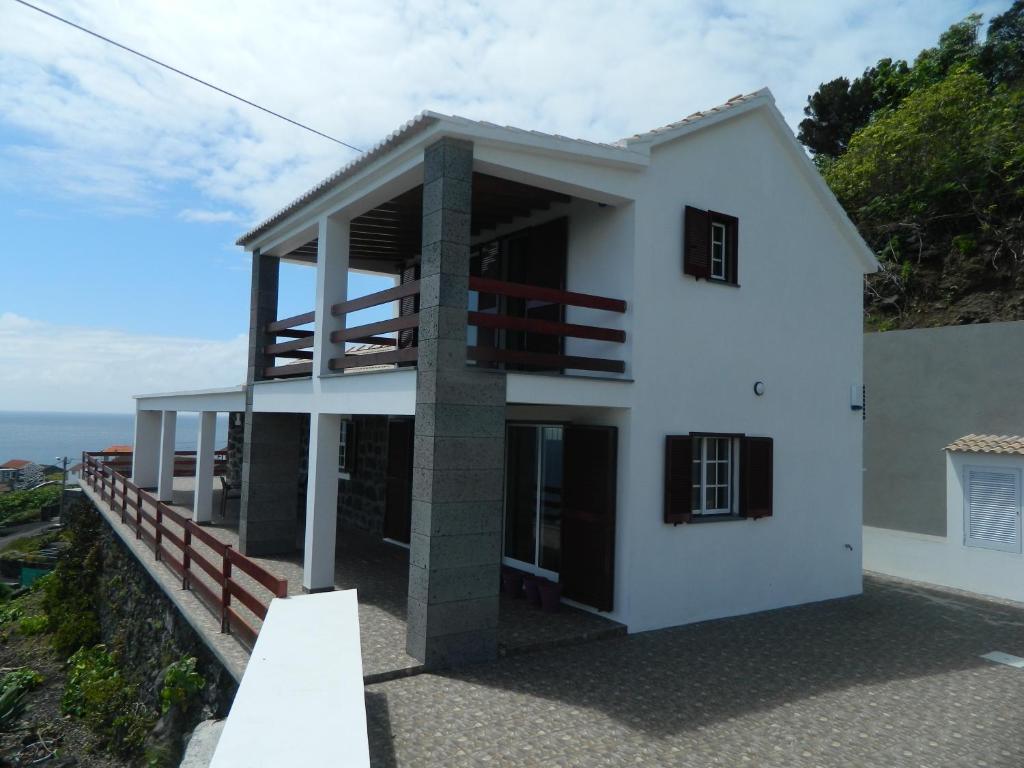 Calheta de NesquimAdega Ninho da Cagarra的山丘上带阳台的白色房屋