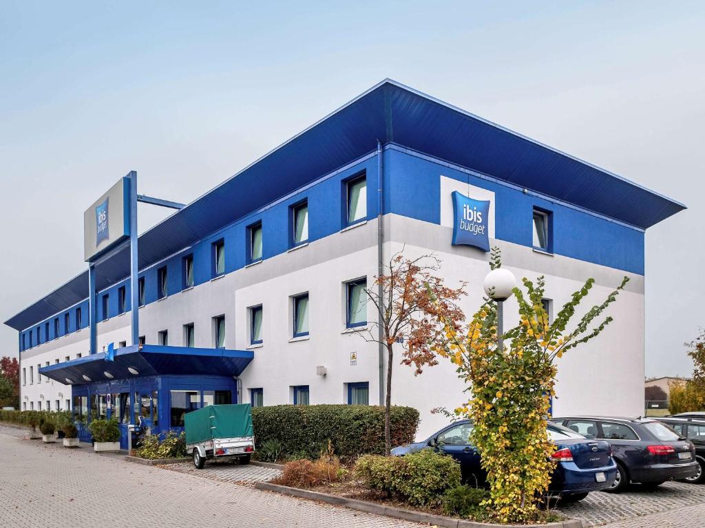 威斯巴登威斯巴登诺丹斯塔德宜必思快捷酒店 的一座蓝色和白色的大建筑,停车场有车辆停放
