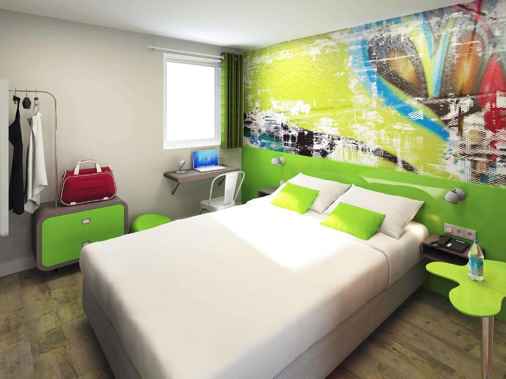 维勒班Ibis Styles Lyon Villeurbanne Parc de la Tête d'Or的卧室配有一张大床,墙上挂有绘画作品