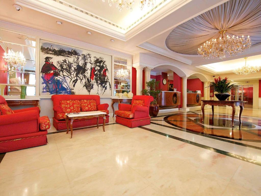 帕尔马帕尔马司汤达美居酒店的客厅配有红色家具和吊灯。
