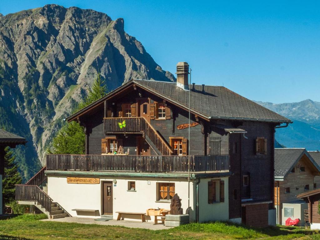 Rosswald瓦莱阿尔卑斯风格格鲁鹏豪斯旅舍的带阳台的房屋,后方是山脉