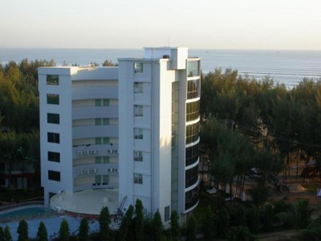 库克斯巴扎派罗塞德酒店的一座白色的建筑,前面有一个游泳池