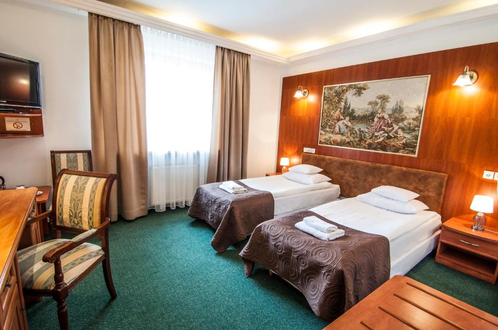 克拉科夫阿图尔酒店的酒店客房,配有两张床和椅子