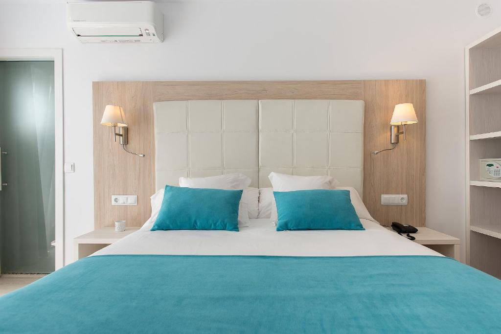 休达德亚Hostal Menurka的一间卧室配有一张带蓝色枕头的大床