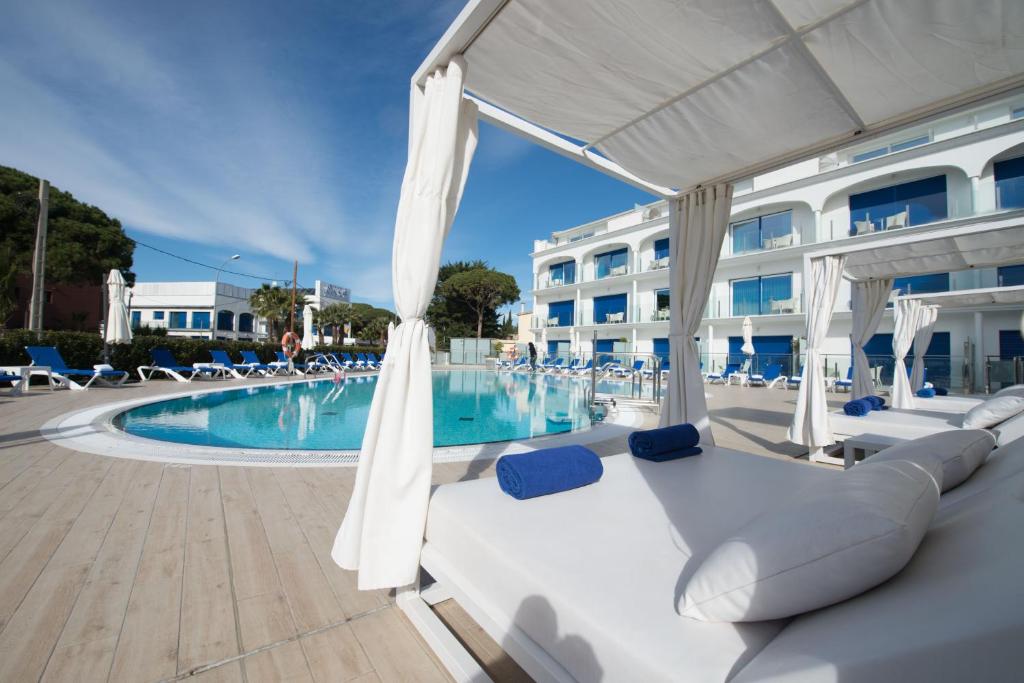 卡斯特尔德费尔斯马思德地中海Spa公寓式酒店的一个带椅子和白色遮阳伞的游泳池