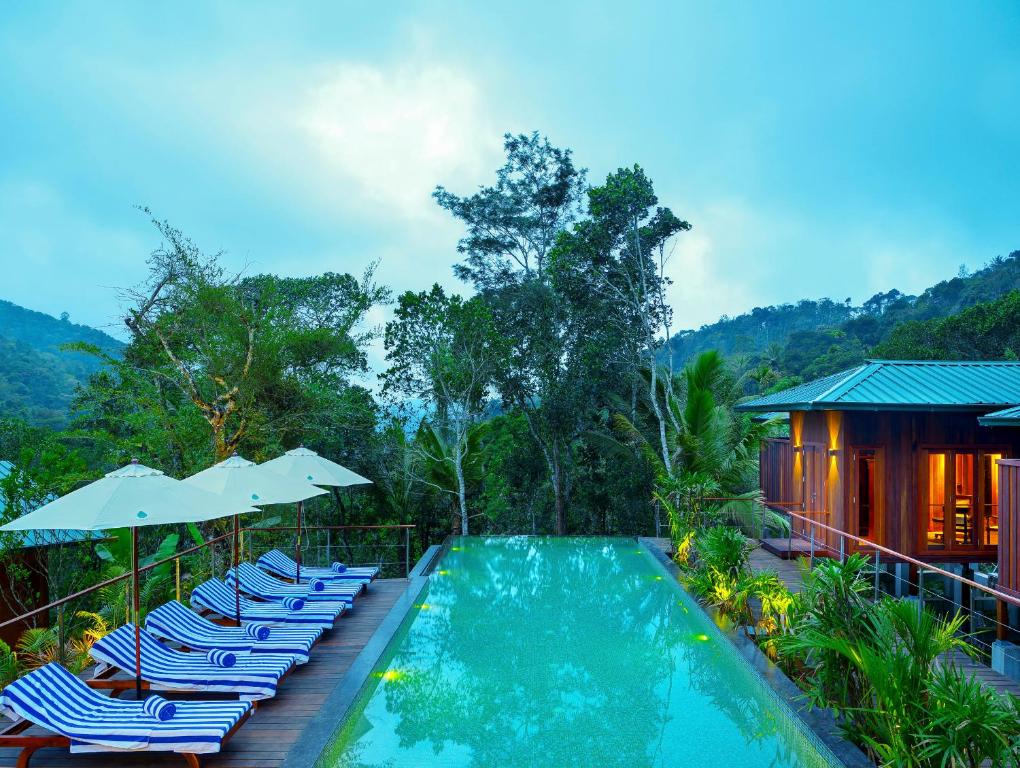提喀迪尼拉马亚豆蔻俱乐部度假酒店的房屋旁的游泳池配有椅子和遮阳伞