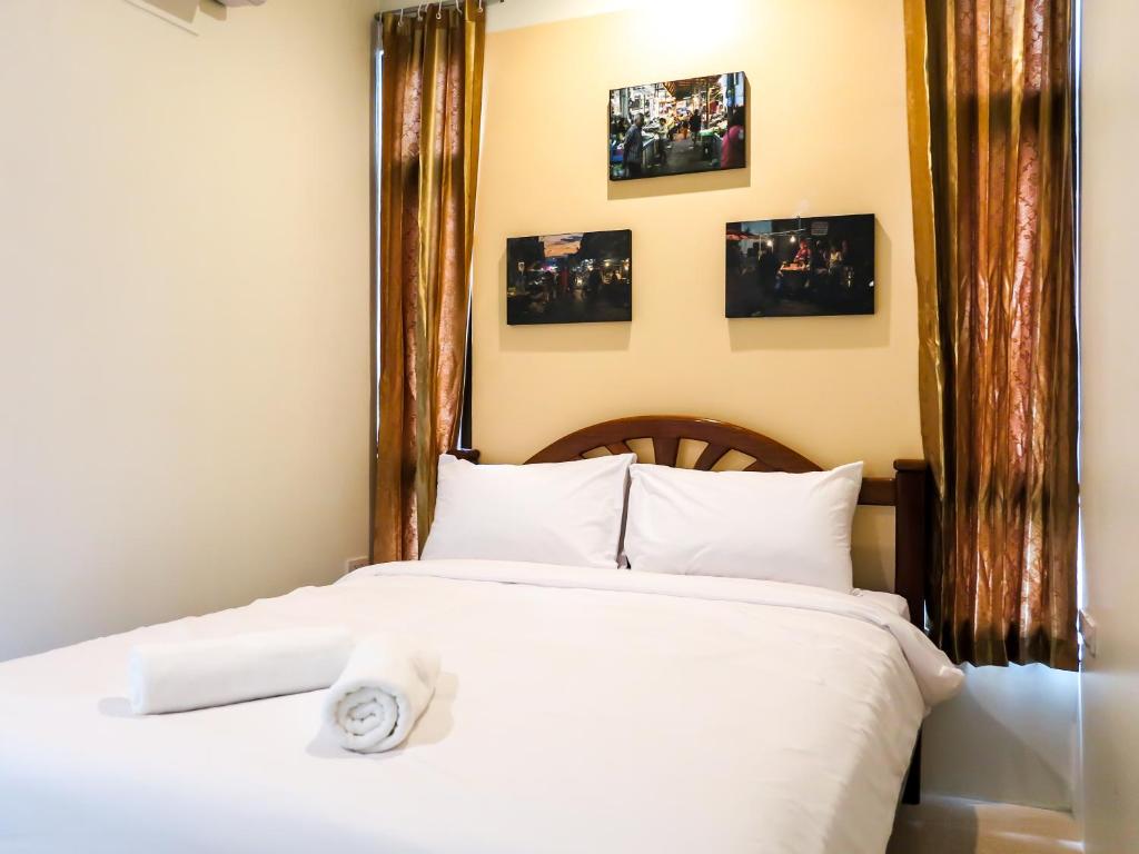 Nang Rongโรงแรมนางรอง的一间卧室配有一张铺有白色床单的床,墙上挂有图片