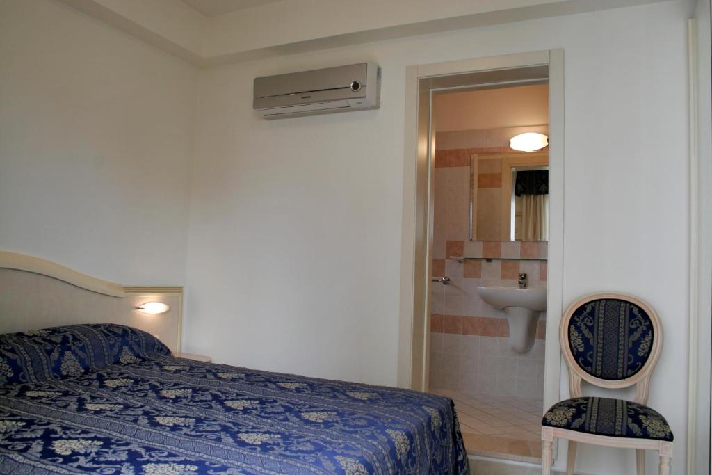 里米尼奥林波公寓式酒店的一间卧室配有一张床,浴室设有水槽