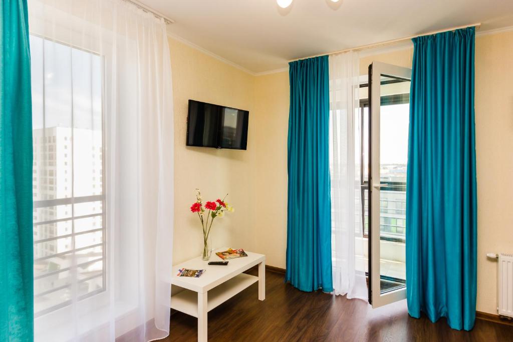 秋明Apartments in Novin Kvartal的一间设有蓝色窗帘和花瓶的桌子的房间