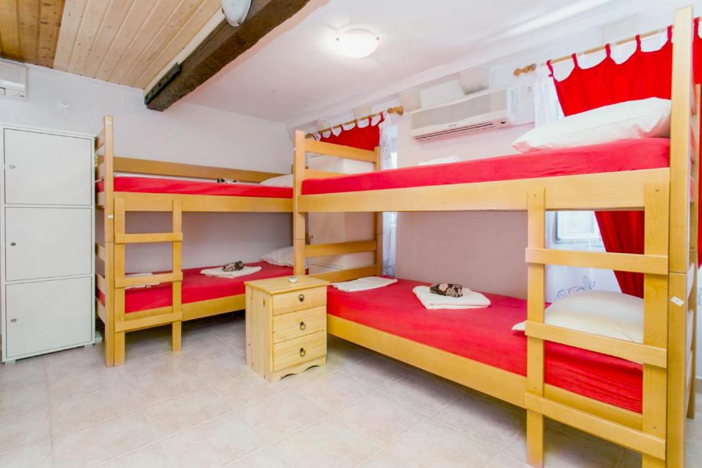 杜布罗夫尼克The City Place Hostel的一间卧室配有两张双层床,铺有红色床单