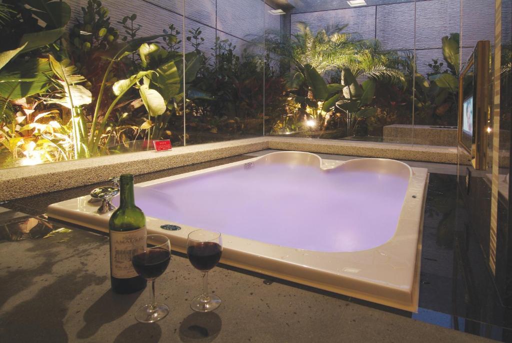 土城区Q Motel精品旅館的浴缸配有2杯葡萄酒和1瓶葡萄酒
