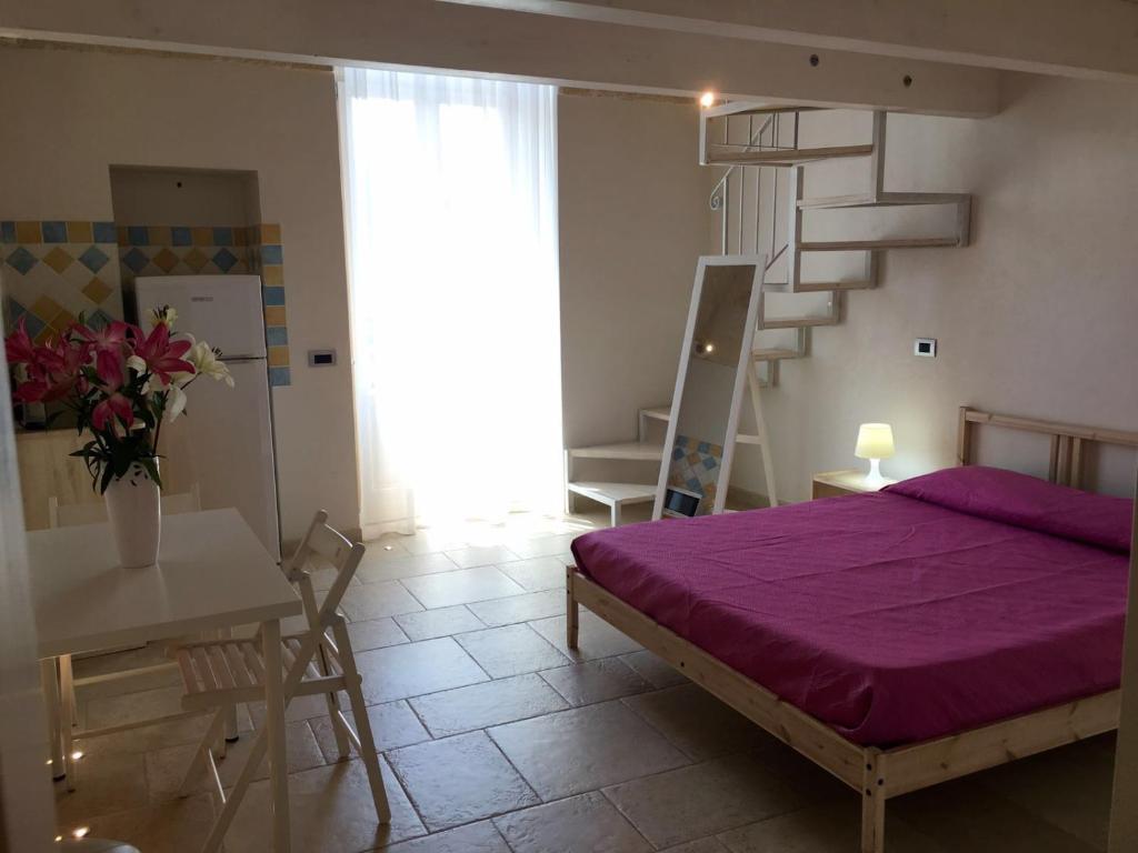滨海波利尼亚诺坎特努纳住宿加早餐旅馆的一间卧室设有紫色的床和楼梯。