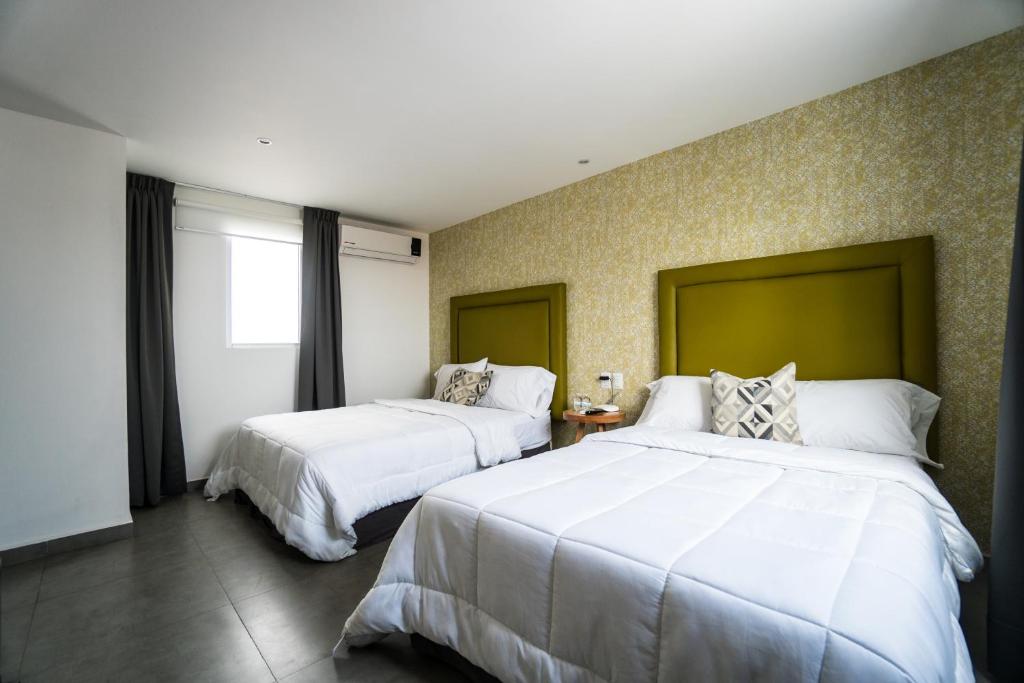 韦拉克鲁斯Hotel Suites Regina的酒店客房设有两张床和窗户。