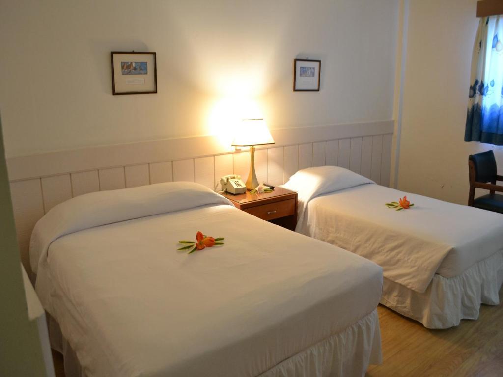 科罗尔市中心西广场酒店的两张位于酒店客房的床,上面有鲜花