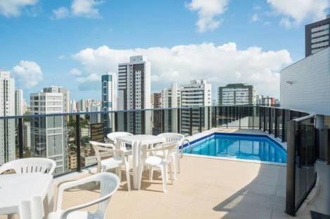 累西腓Jaqueira Home Service的一个带白色桌椅的阳台和一个游泳池